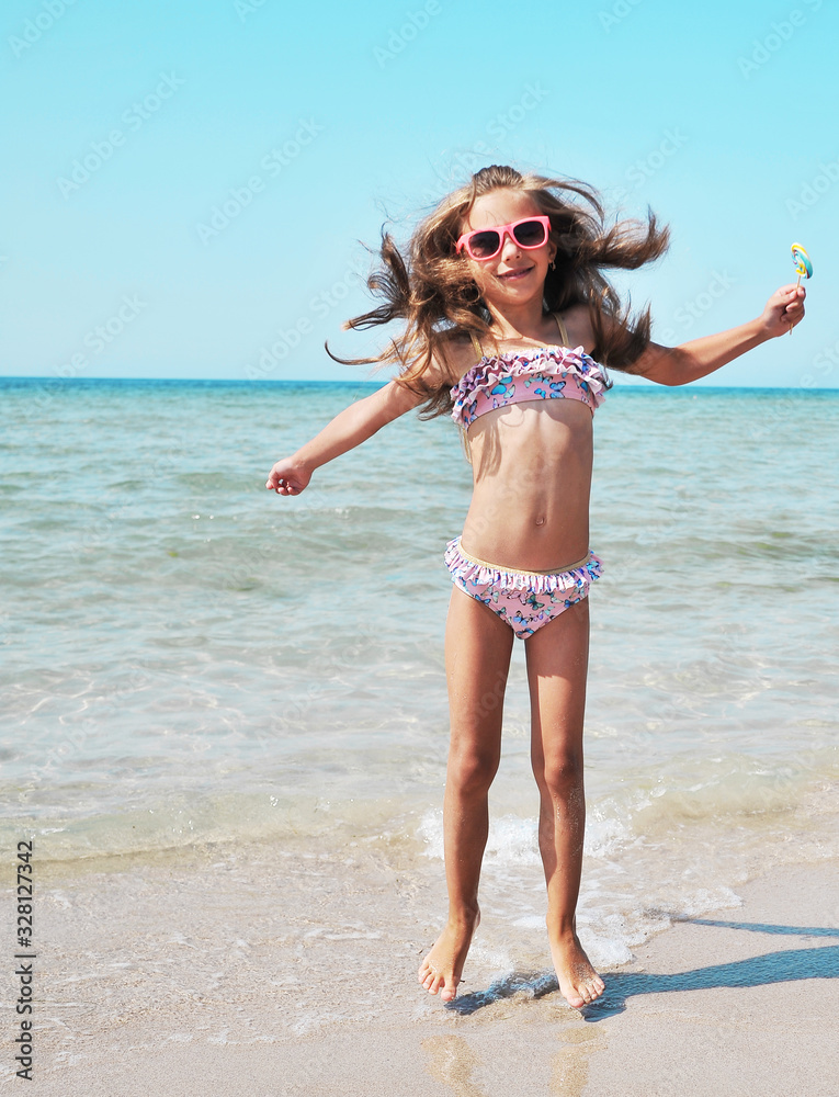 Naklejka premium Summertime. Little girl has fun on the beach. Summer concept.