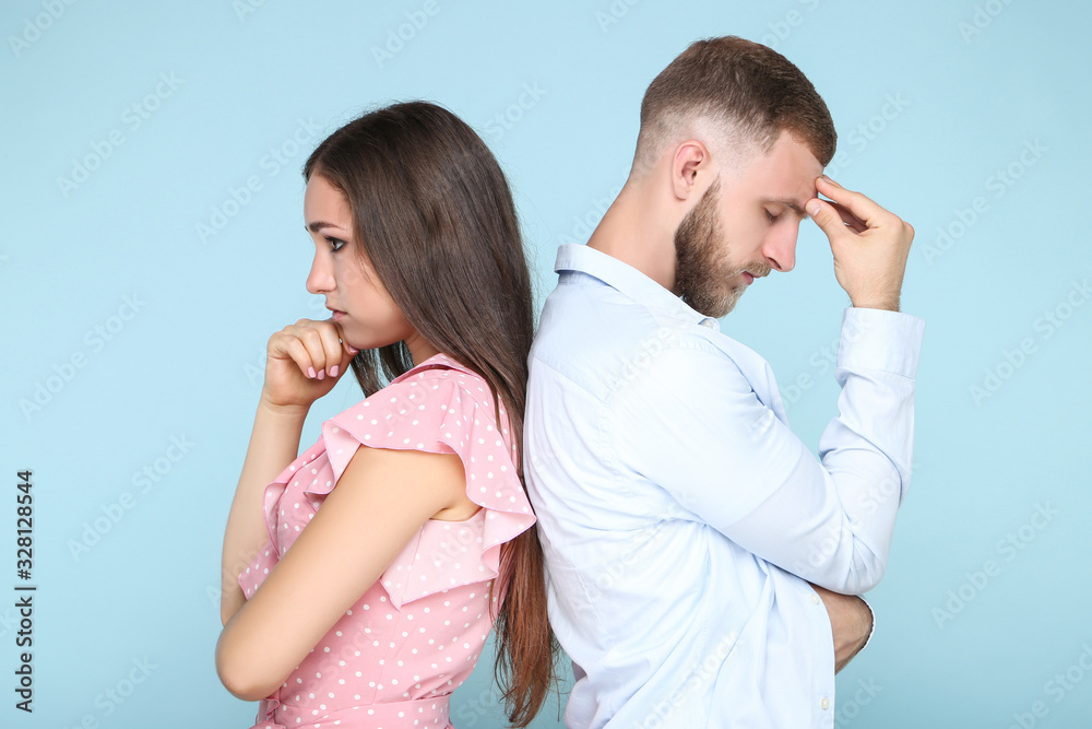 Young upset couple standing by the back to each other on blue background Young upset couple standing by the back to each other on blue background