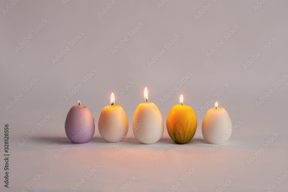 Burning candles in the form of eggs. Candles of different colors Burning candles in the form of eggs. Candles of different colors