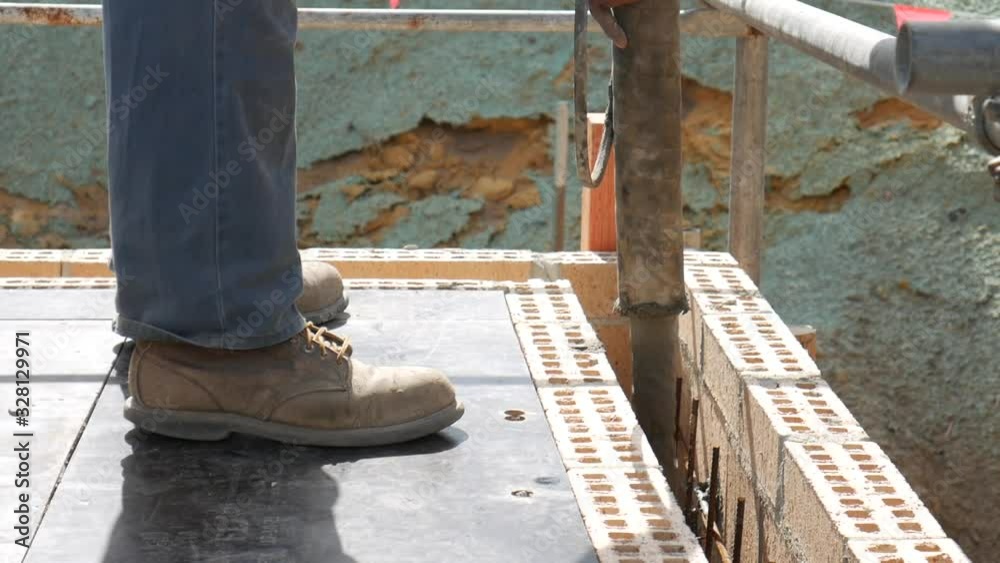 Tradie worker pouring concrete in between bricks on a construction site Tradie worker pouring concrete in between bricks on a construction site