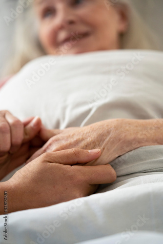 Close-up of home carer consoling senior female patient at nursing home