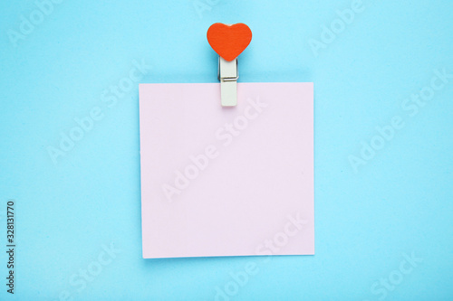Paper sticky note with clothespin on blue background