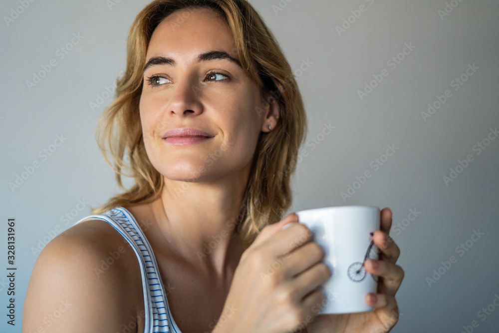 Thoughtful young woman holding coffee mug against white background Thoughtful young woman holding coffee mug against white background