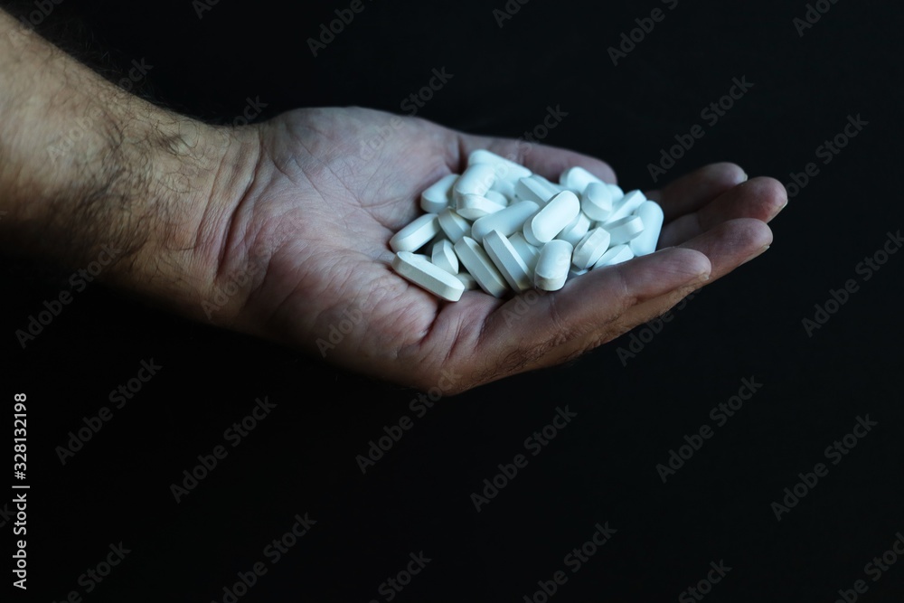 Handful of white pharmaceutical pills against black background Handful of white pharmaceutical pills against black background