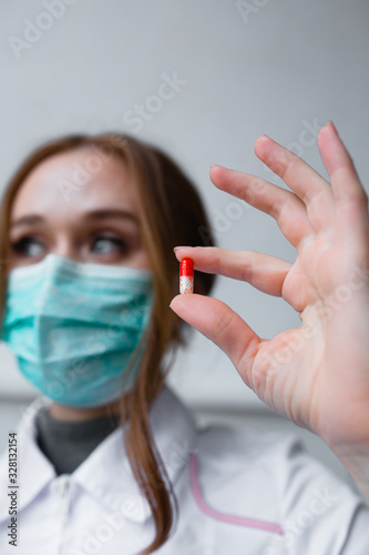 Medicine concept - beautiful girl doctor holds pill for disease