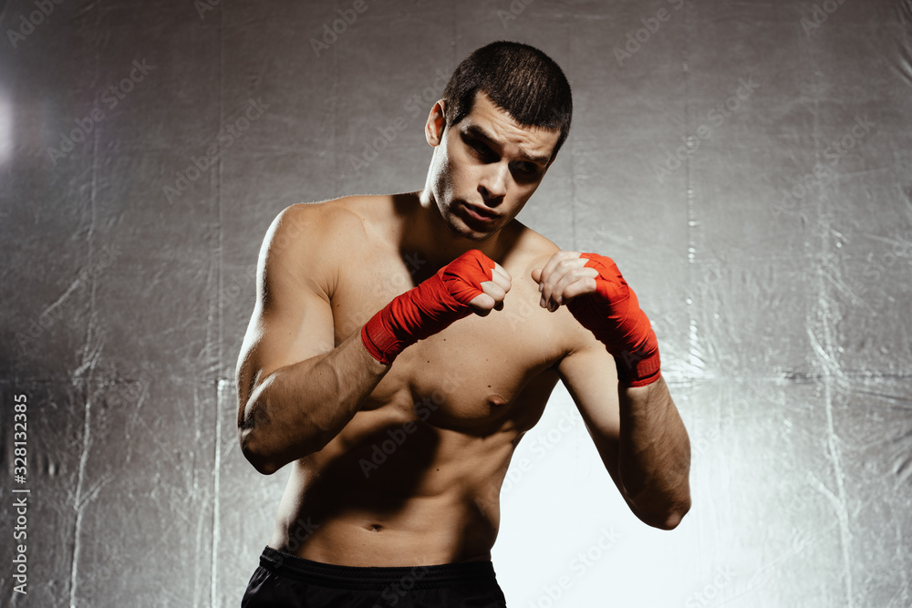 Athletic boxer punching with determination and precaution over silver kground