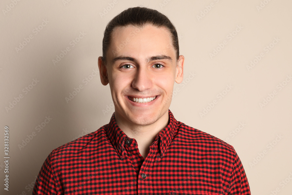 Portrait of happy young man on beige background