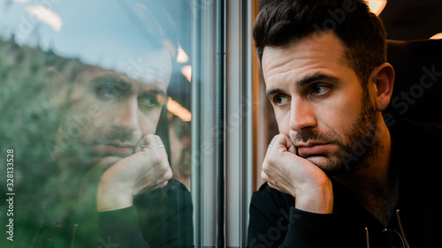 Young bearded man traveling by train in late afternoon photo