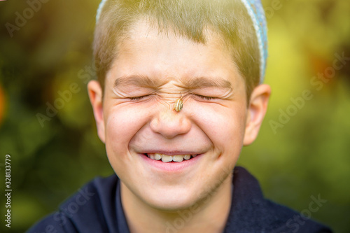 a boy in the sunlight with a snail on his face