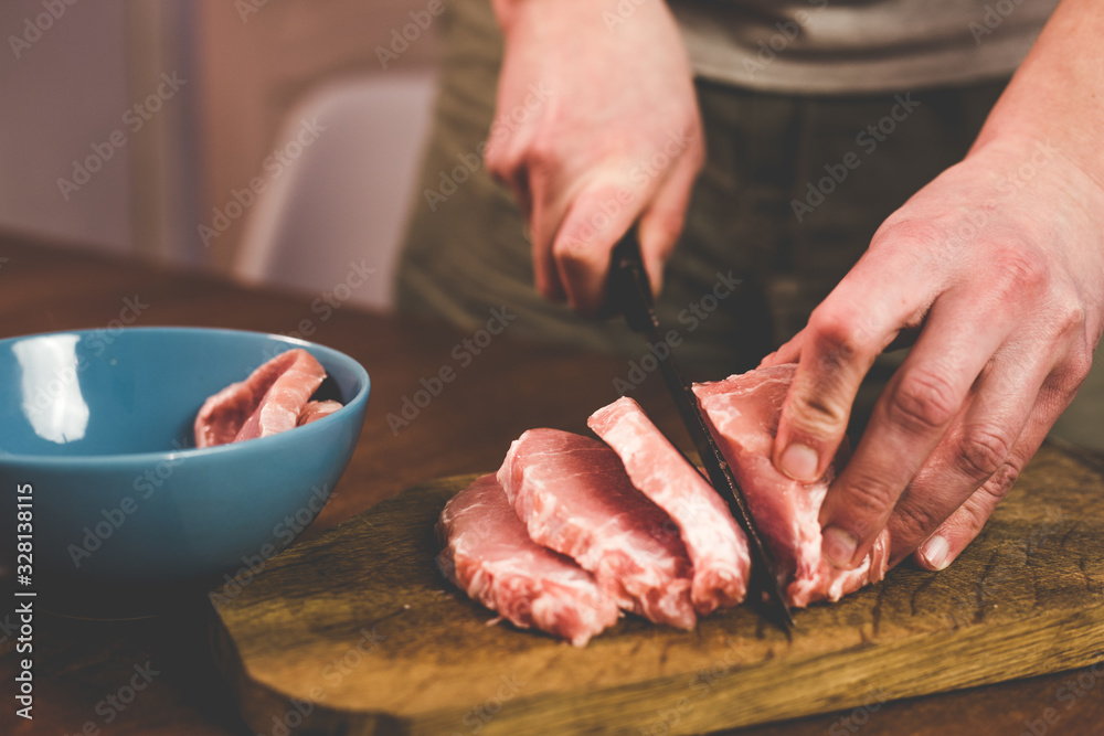 I cut pork with a knife on a wooden board