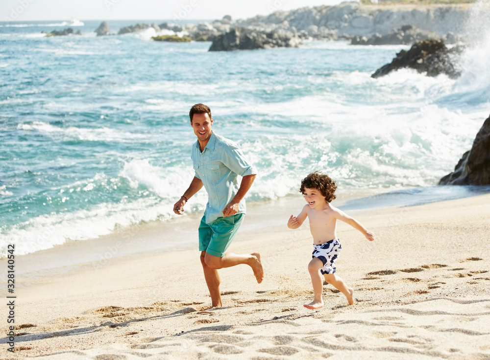 Father and son running on the beach on vacation in Mexico Father and son running on the beach on vacation in Mexico