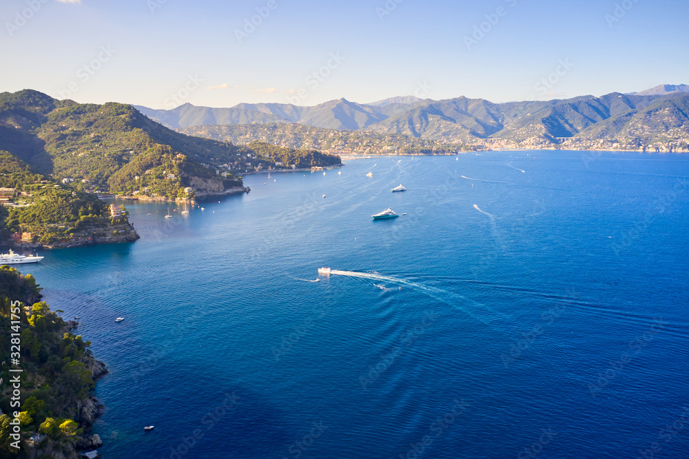Arial view on yachts and boats, sailing in the Ligurian Sea on the mountain background, Portofino, Italy. Rocks and hills seaside with the traditional Italian houses on the top.