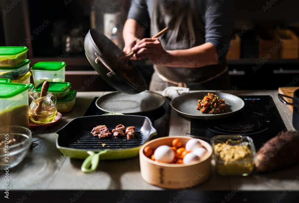 Man cooking delicious food in frying pan on electric stove Man cooking delicious food in frying pan on electric stove