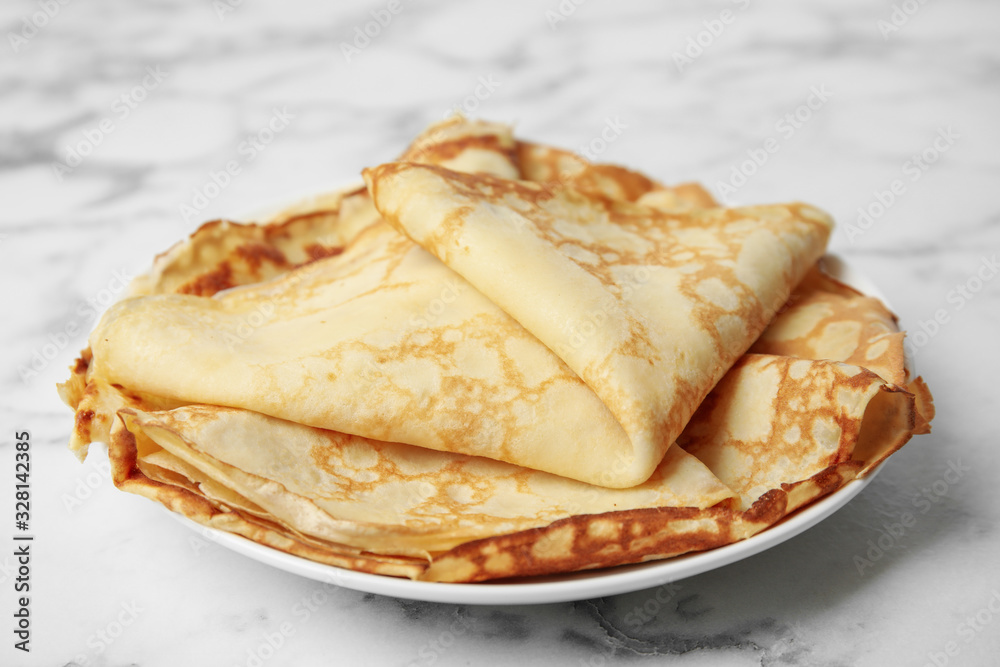 Stack of fresh thin pancakes on white marble table Stack of fresh thin pancakes on white marble table
