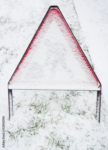 Road works warning sign covered in snow hiding the man at work symbol, UK.