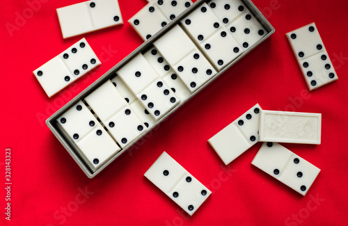 Dominoes Old domino bones lie in a gray case and near it on a red fabric background and a lot of space for text