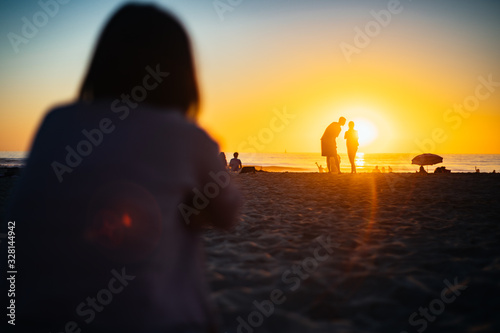 A Girl Looking at the Silhouettes of Couple with sunset photo