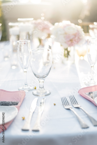 Bright Modern and Elegantly Arranged Wedding Table Setting with Pink and White Roses and Crystal Clear Glasses with Sunset Background at Beautiful Reception in Tropical Island Paradise of Maui Hawaii 