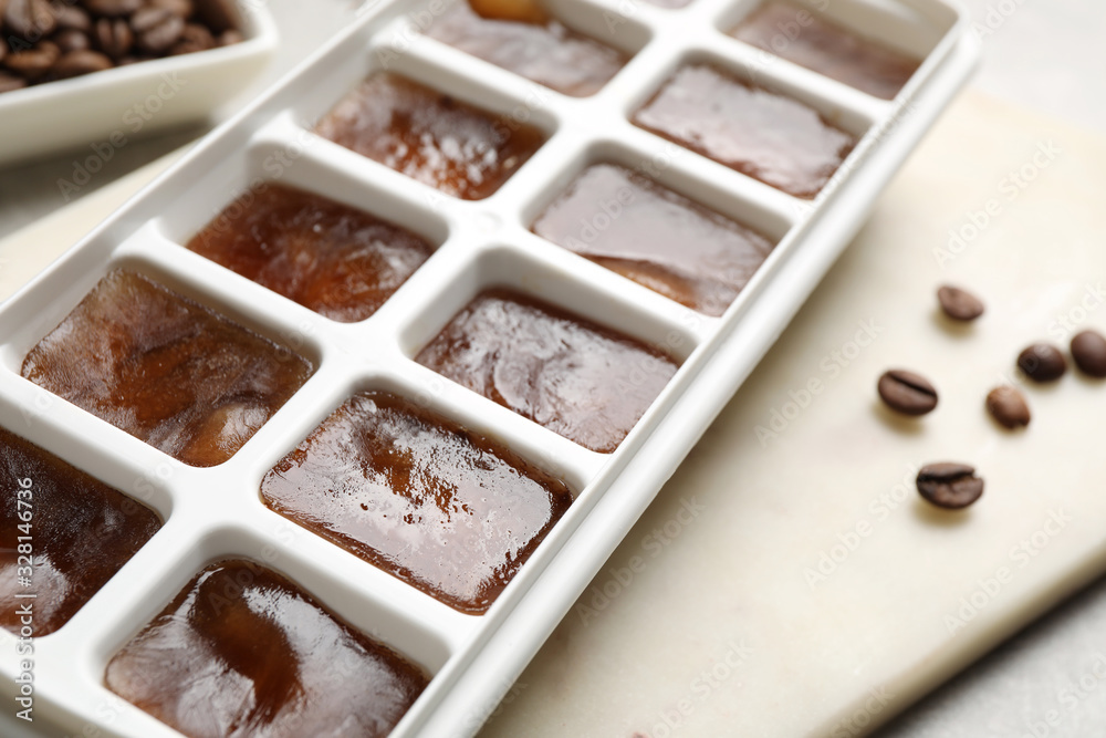 Ice cubes in tray and coffee beans on grey table, closeup Ice cubes in tray and coffee beans on grey table, closeup