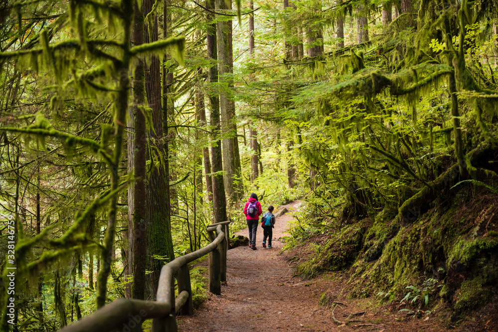 Mother and kid walking on trail in the forest. Mother and kid walking on trail in the forest.