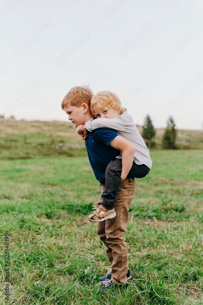 Older brother giving piggyback ride to his younger brother Older brother giving piggyback ride to his younger brother