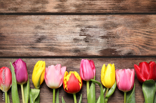 Beautiful spring tulips on wooden table, flat lay. Space for text
