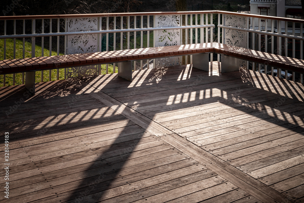 Staircase with benches with a shadow from the railing. Staircase with wooden steps and a shadow from the railing. A play of light and shadow in the evening. Staircase with benches with a shadow from the railing. Staircase with wooden steps and a shadow from the railing. A play of light and shadow in the evening.
