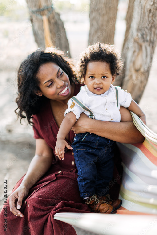 An African American mother and her child outdoors in a hammock. An African American mother and her child outdoors in a hammock.