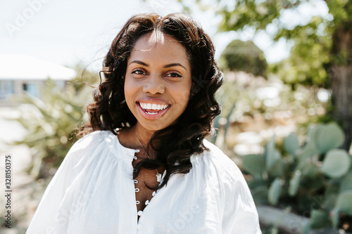 Portrait of smiling young black woman with sunlight flare and copy space photo