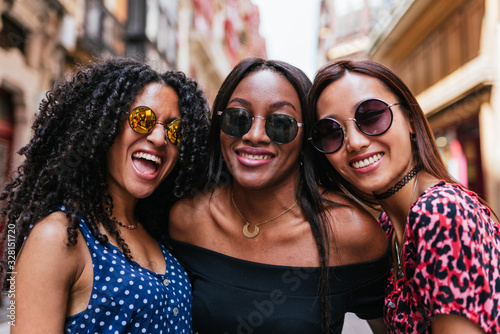 Brown skinned women wearing sunglasses and laughing together. photo