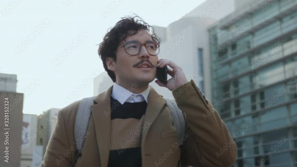 Businessman talking on smartphone at street. Professional walking with phone