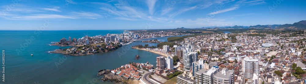 Beautiful drone view of Guarapari city center with beaches, houses and buildings on the waterfront streets and transparent sea on a sunny summer day with blue sky. Espirito Santo state, Brazil.