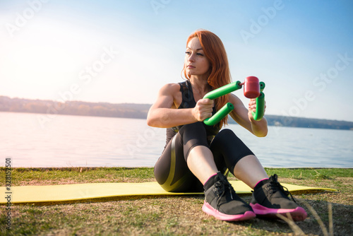 Fototapeta Naklejka Na Ścianę i Meble -  Beautiful  young female doing exercises on the street of the playground. Concept of good physical shape and healthy lifestyle