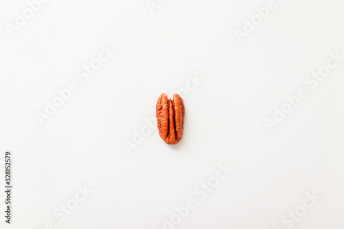 Brown pecan nut half isolated on a grey background, top view, flat style