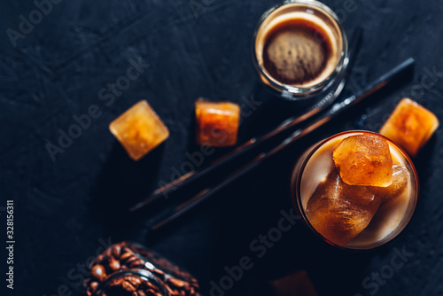 Iced coffee in a glass with ice cubes on black wooden background,metal zero waste straw for cocktails,top view