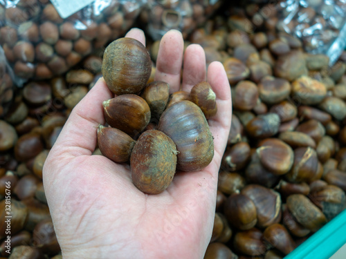 lady holding fresh organic chestnuts at the super market