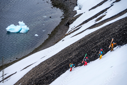 Group of friends skinning up mountain to ski in Svalbard photo