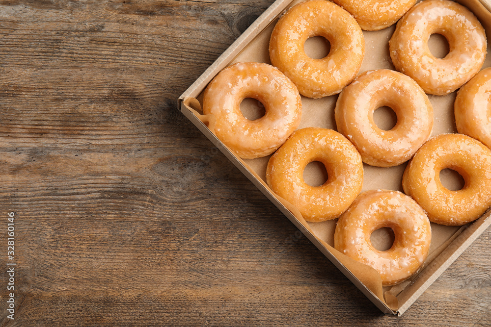 Delicious donuts on wooden table, top view. Space for text
