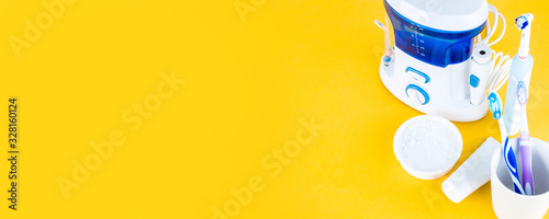 Irrigator, toothbrush and toothpaste on a yellow background. Space for text or design photo