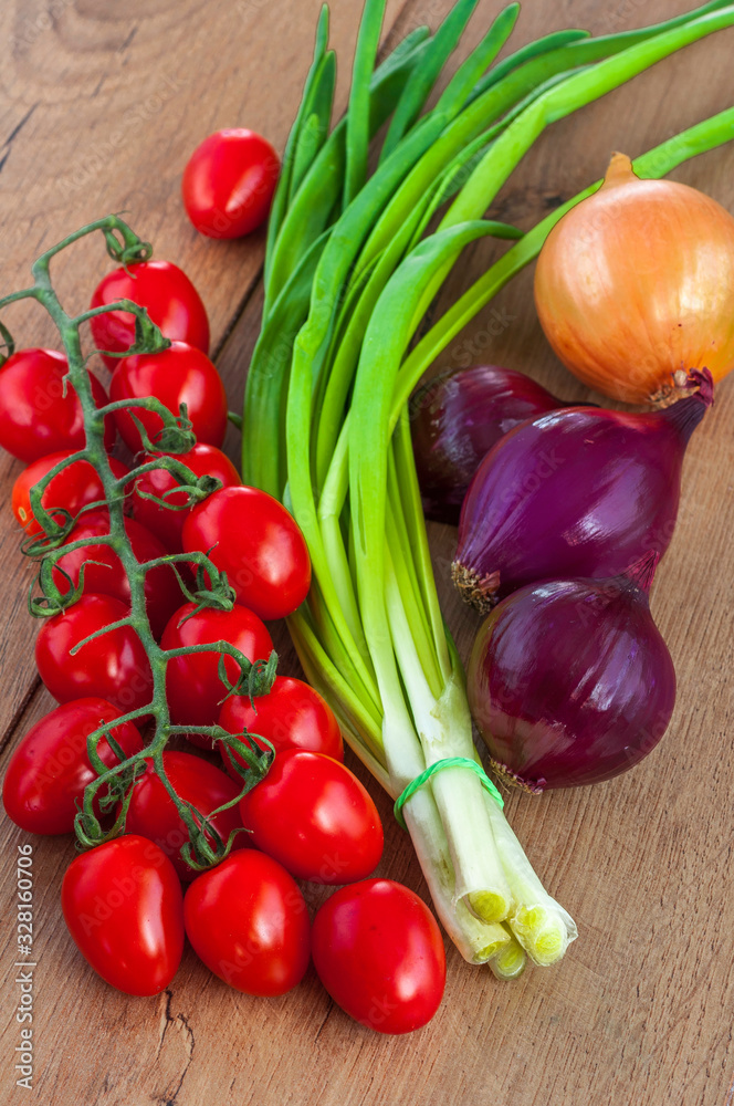 Red cherry tomatoes on a branch and green onions Red cherry tomatoes on a branch and green onions