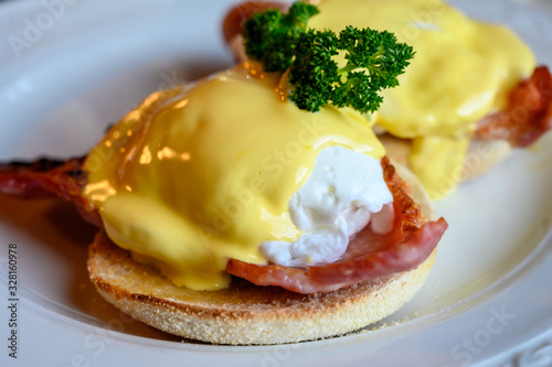 Weekend brunch in Scotland with two eggs benedict on homemade muffuns with roasted bacon and yellow hollandaise sauce. photo