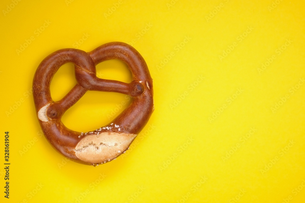 Bretzel on a bright yellow background. Bagel baking on yellow. German and Austrian traditional pastries. Oktoberfest food Bretzel on a bright yellow background. Bagel baking on yellow. German and Austrian traditional pastries. Oktoberfest food