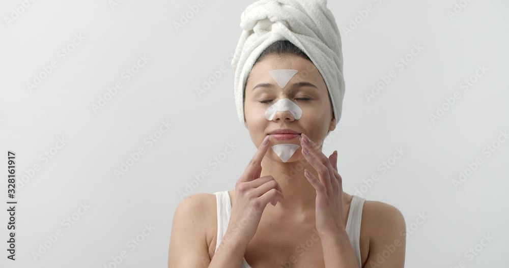 Cheerful lady posing in studio with white skin stickers on nose, chin and forehead. Isolated over white background. Concept of cleansing procedure Cheerful lady posing in studio with white skin stickers on nose, chin and forehead. Isolated over white background. Concept of cleansing procedure