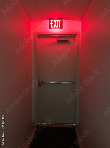 Emergency exit door at the end of the hall with the exit light on Fototapeta