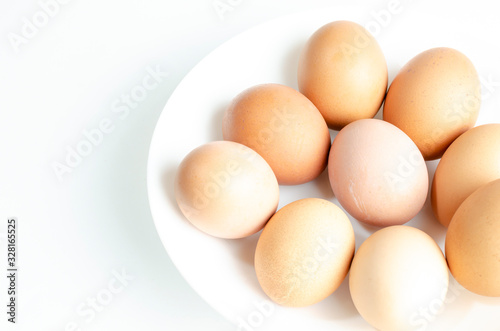 fresh brown eggs on a white plate in a deep plate