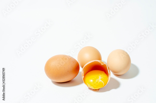 a group of fresh brown chicken eggs on a white background and one broken