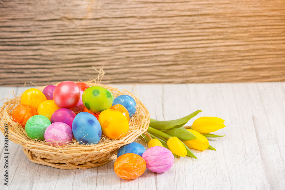 Beautiful group Easter eggs in the spring of easter day, red eggs, blue, purple and yellow in Wooden basket with tulips on the  wood table background