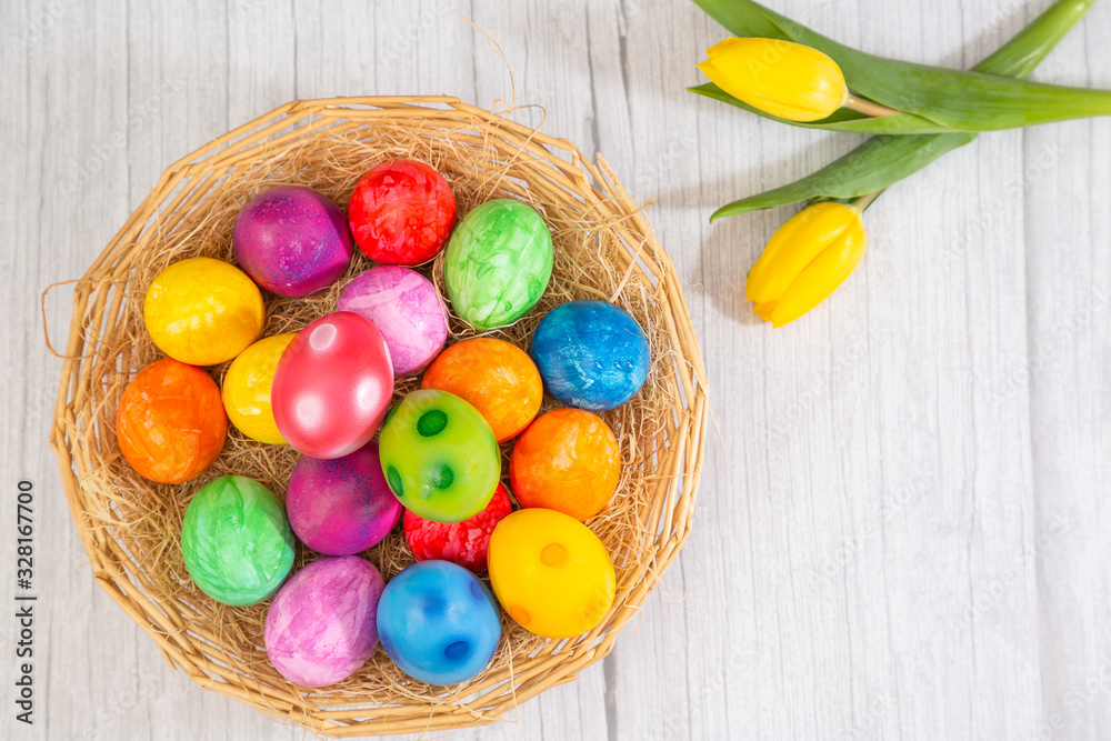 Beautiful group Easter eggs in the spring of easter day, red eggs, blue, purple and yellow in Wooden basket with tulips on the  wood table background
