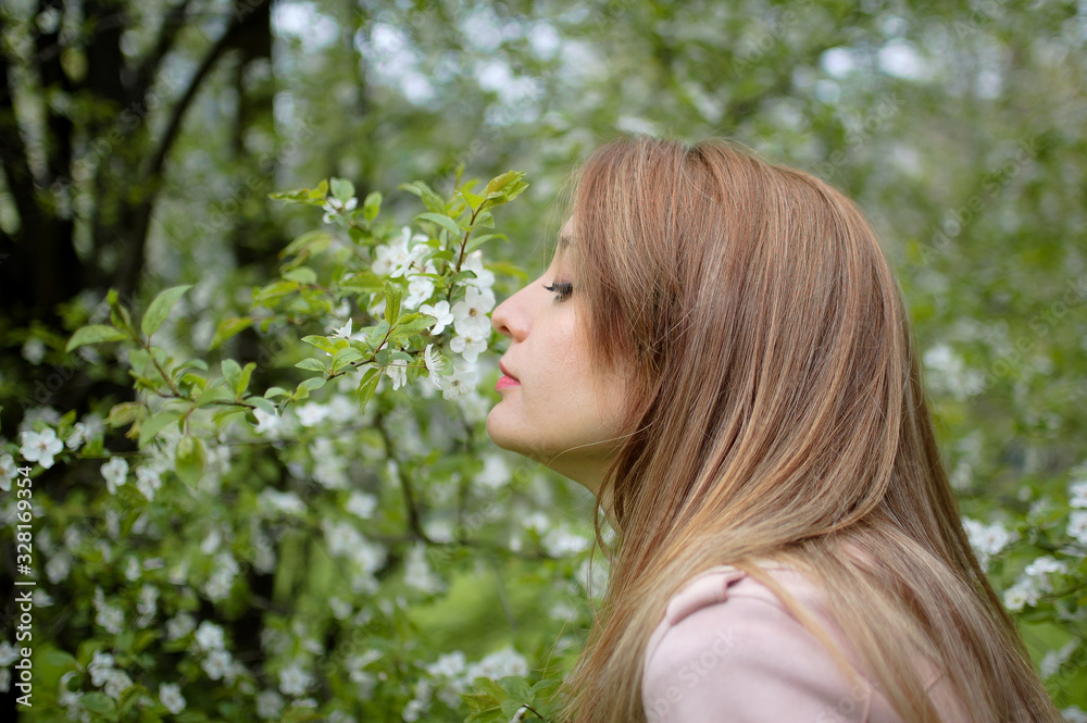 Young pretty woman with a blond hair posing near a big flowering tree in a spring park, outdoors female portrait Young pretty woman with a blond hair posing near a big flowering tree in a spring park, outdoors female portrait