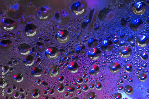 Blue Water drops on the surface of the glass with reflections of bright spots of color.